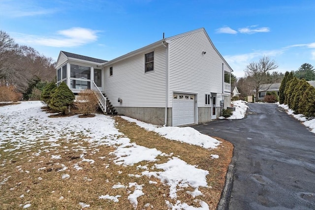 view of snow covered exterior featuring a garage and a sunroom