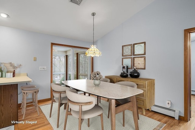 dining area featuring lofted ceiling, light hardwood / wood-style flooring, and a baseboard heating unit