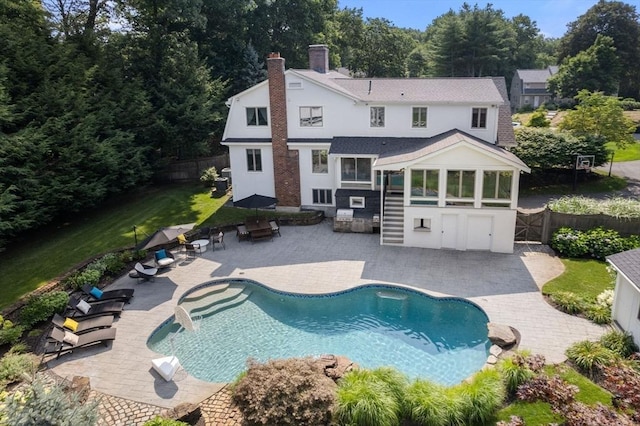 19 Buckmaster Dr, Sudbury, MA 01776 - back of house with a sunroom, a fenced backyard, a fenced in pool, a chimney, and a patio
