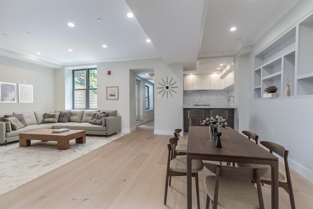 dining area with built in features, crown molding, and light hardwood / wood-style flooring