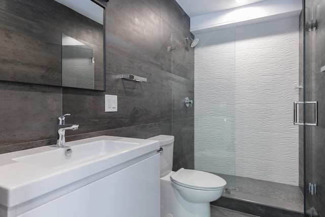 bathroom with vanity, toilet, walk in shower, and tile walls