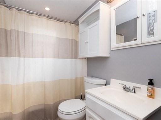 bathroom with toilet, curtained shower, recessed lighting, and vanity