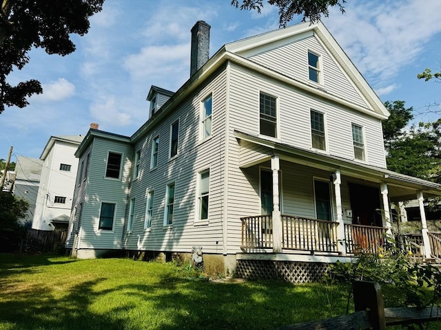 view of front of home featuring a chimney, a porch, and a front yard