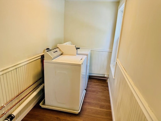 laundry room featuring laundry area, dark wood-style flooring, a wainscoted wall, and washing machine and clothes dryer