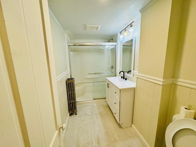 bathroom featuring toilet, wainscoting, a shower stall, vanity, and wood finished floors