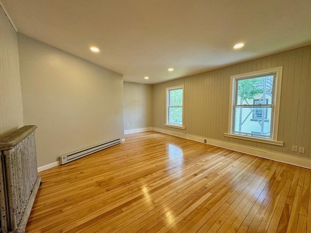 empty room with light wood-style floors, baseboards, baseboard heating, and recessed lighting