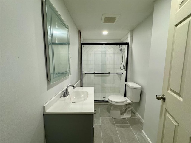 bathroom with a shower stall, baseboards, vanity, and toilet