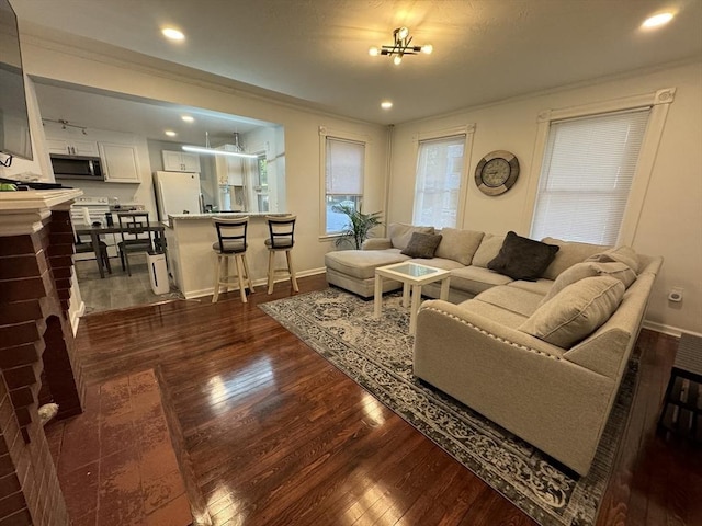 living area featuring recessed lighting, dark wood-style flooring, crown molding, and baseboards