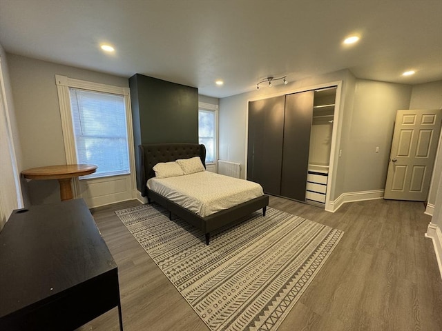 bedroom with a closet, recessed lighting, wood finished floors, and baseboards