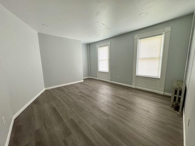 empty room with radiator heating unit, dark wood finished floors, and baseboards