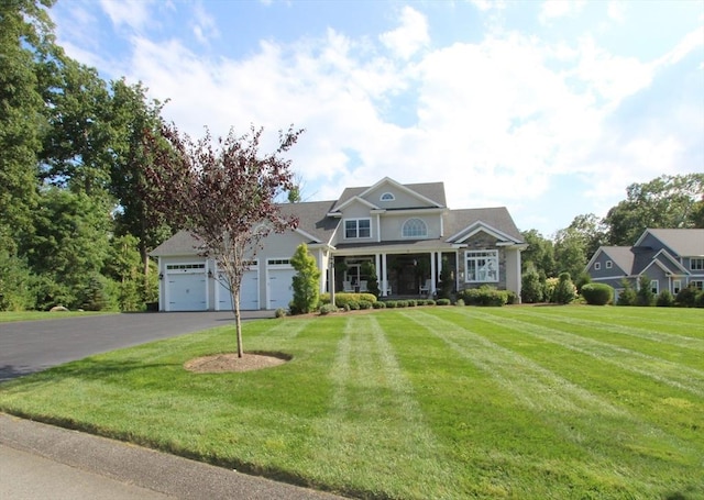 view of front of home featuring a garage, a front yard, and covered porch