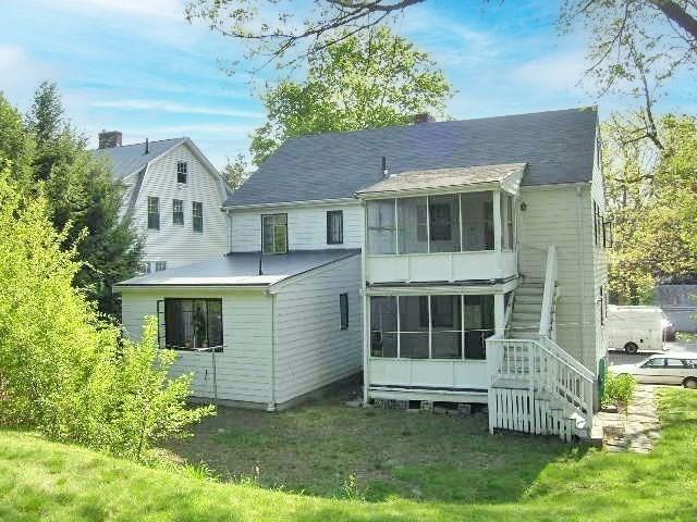 back of house with a sunroom, stairs, and a yard