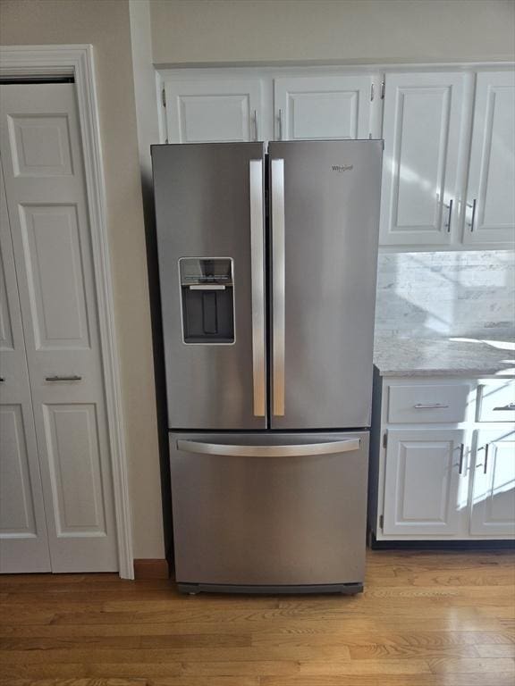 kitchen with white cabinets, stainless steel fridge, and light hardwood / wood-style flooring