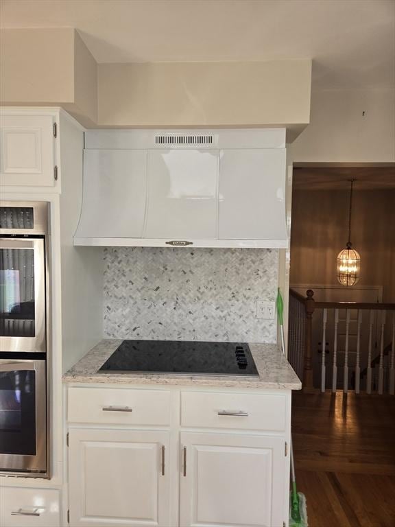 kitchen featuring white cabinets, black electric cooktop, and backsplash