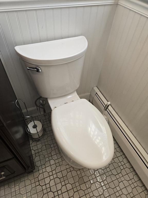 bathroom featuring tile patterned flooring, toilet, and baseboard heating