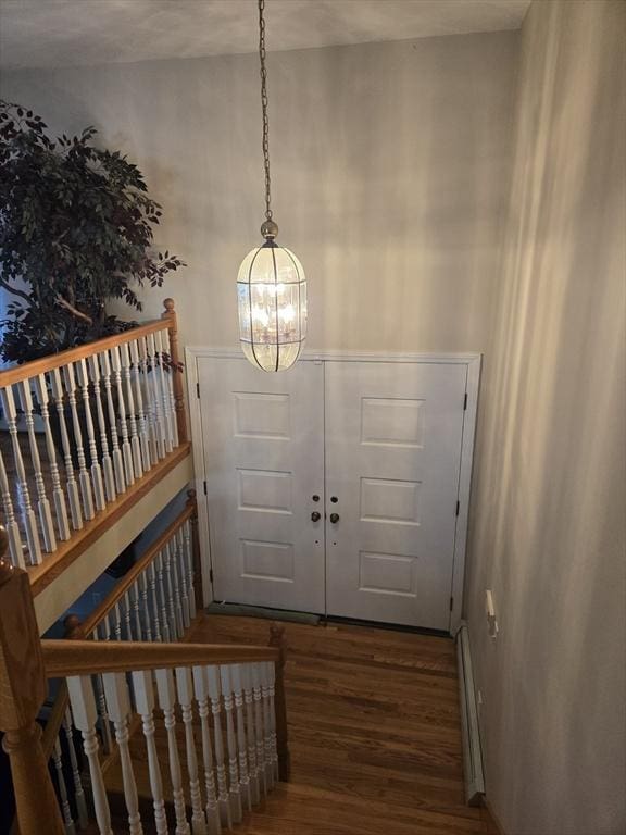 entrance foyer featuring hardwood / wood-style floors, a baseboard radiator, and an inviting chandelier