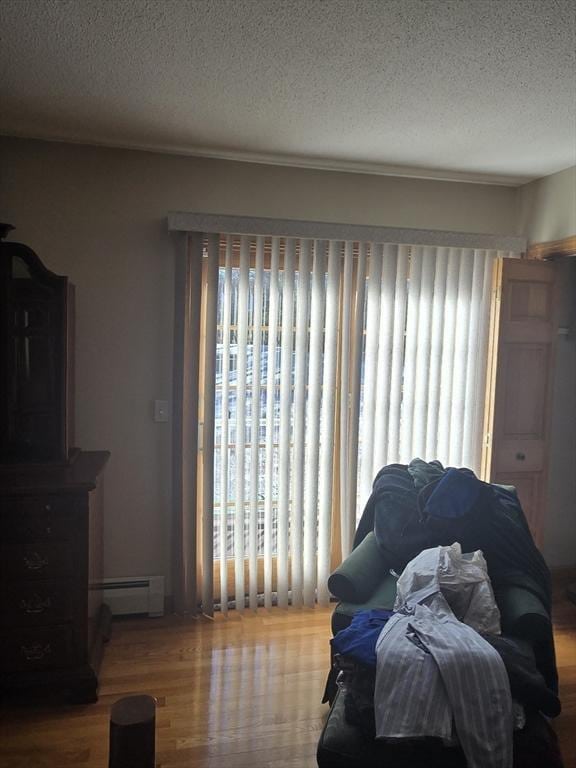 bedroom featuring wood-type flooring, a textured ceiling, and baseboard heating