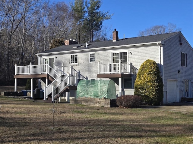 rear view of house with a lawn, a deck, and a garage