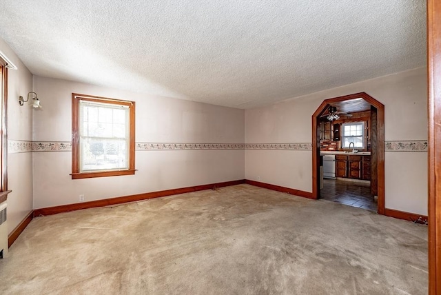 carpeted spare room featuring ceiling fan, sink, a textured ceiling, and radiator