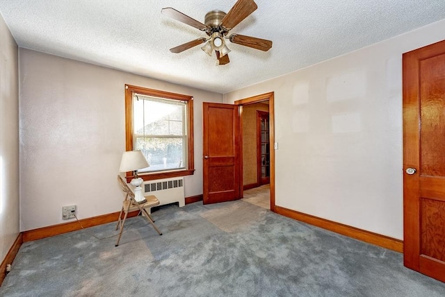 carpeted spare room featuring radiator heating unit, a textured ceiling, and ceiling fan