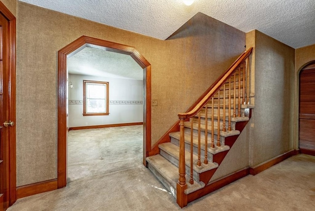 stairs featuring carpet and a textured ceiling