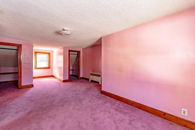 unfurnished bedroom featuring light colored carpet, radiator heating unit, and a textured ceiling