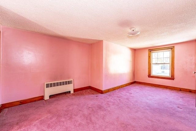 empty room featuring carpet floors, a textured ceiling, and radiator