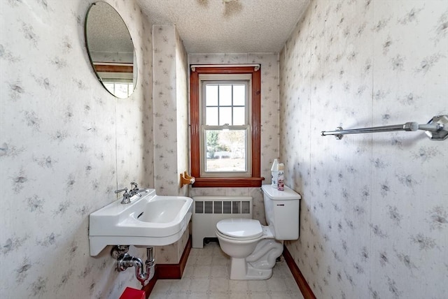 bathroom with toilet, radiator heating unit, and a textured ceiling