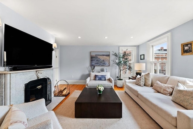 living area with recessed lighting, a fireplace, baseboards, and wood finished floors