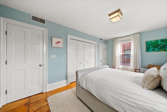 bedroom with wood finished floors, visible vents, and baseboards