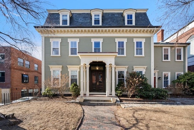 second empire-style home with mansard roof and fence