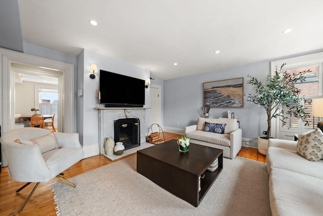 living room with recessed lighting, wood finished floors, baseboards, and a high end fireplace