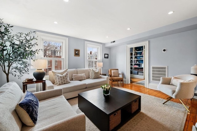 living room with recessed lighting, visible vents, and wood finished floors