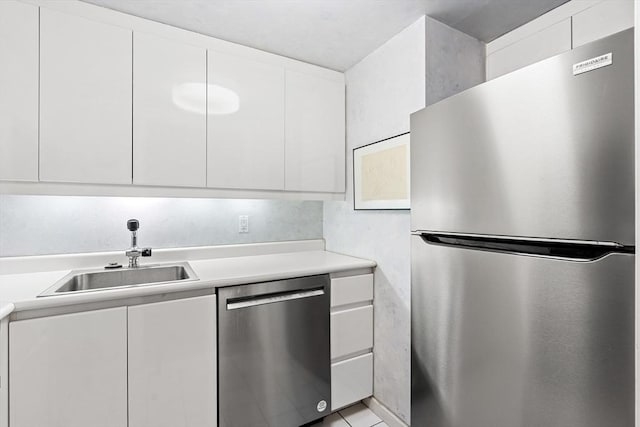 kitchen with a sink, appliances with stainless steel finishes, light countertops, and white cabinetry