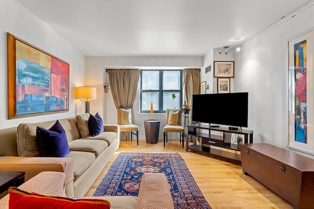 living area featuring visible vents and wood finished floors