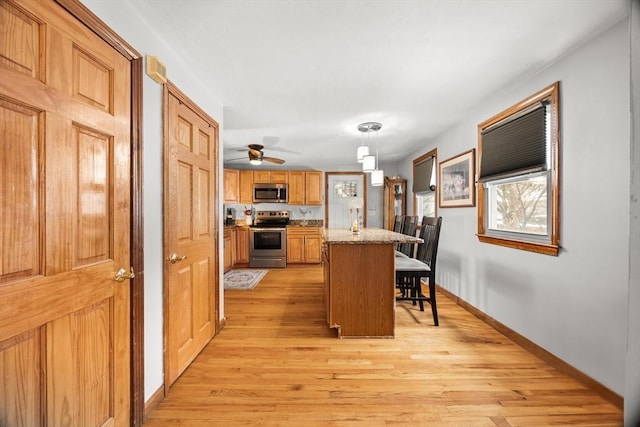 kitchen featuring hanging light fixtures, a breakfast bar area, stainless steel appliances, and light wood-type flooring