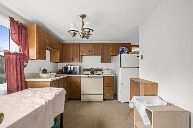 kitchen featuring white appliances, light countertops, a chandelier, and brown cabinets
