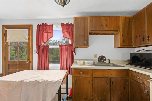 kitchen featuring a sink, light countertops, brown cabinets, and oven