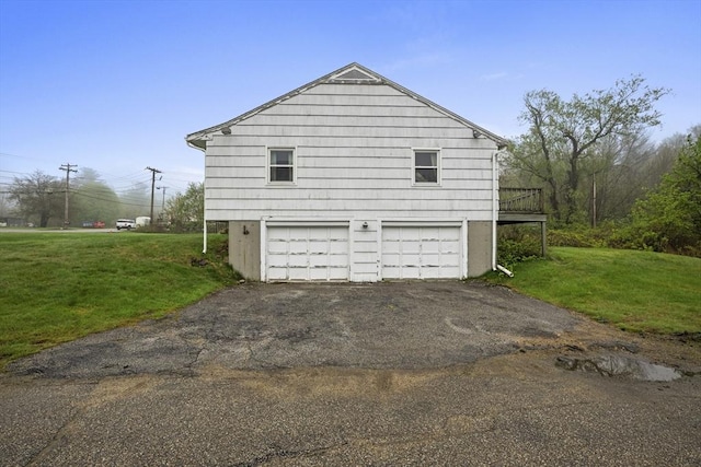 view of side of property featuring driveway, a yard, a garage, and a deck