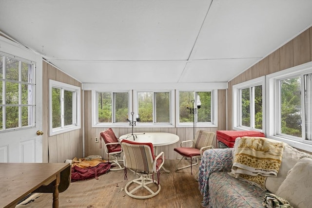 sunroom featuring wood finished floors, lofted ceiling, and wooden walls