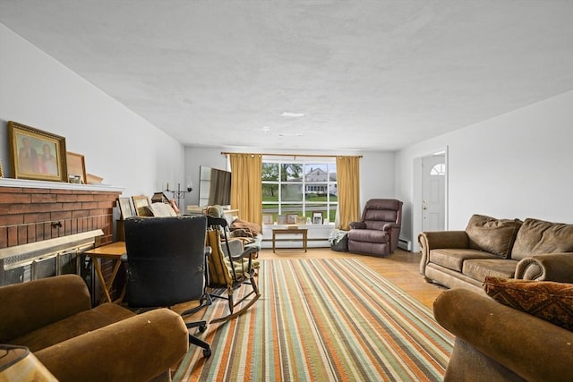 living area with a baseboard radiator, wood finished floors, and a brick fireplace