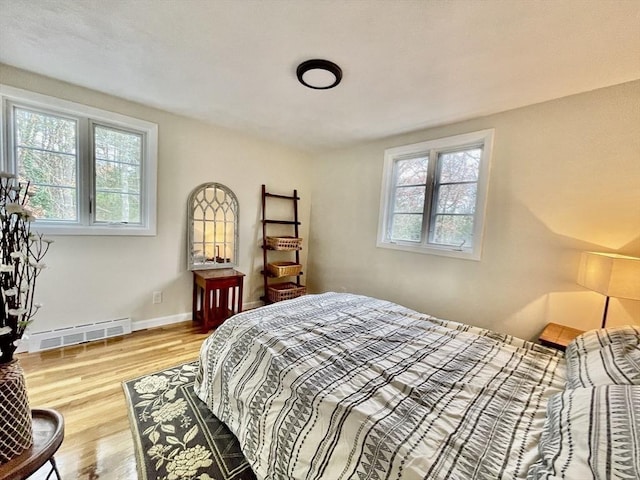 bedroom with light hardwood / wood-style floors and a baseboard radiator