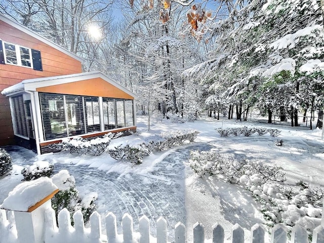 yard layered in snow with a sunroom