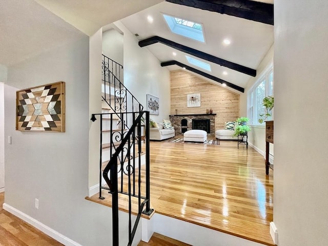 stairway featuring a fireplace, wood-type flooring, beamed ceiling, a skylight, and high vaulted ceiling