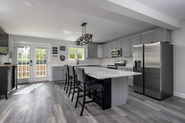 kitchen featuring pendant lighting, appliances with stainless steel finishes, gray cabinetry, a center island, and french doors