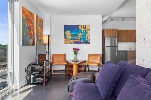 living area featuring concrete flooring, rail lighting, and plenty of natural light