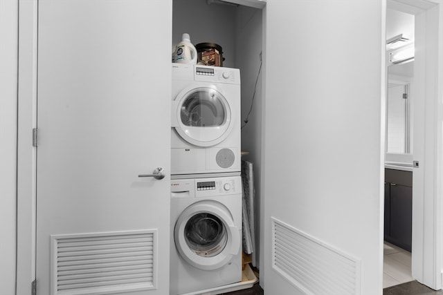 clothes washing area featuring laundry area, tile patterned flooring, and stacked washer / dryer