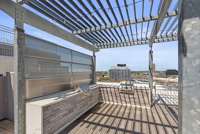 wooden deck with grilling area, a city view, a pergola, and exterior kitchen