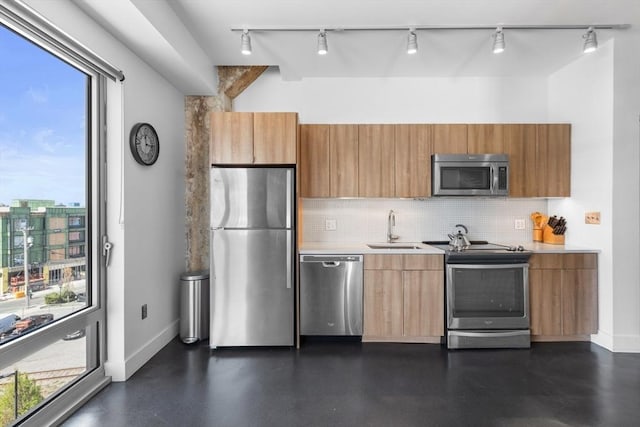 kitchen featuring stainless steel appliances, track lighting, a sink, and a healthy amount of sunlight