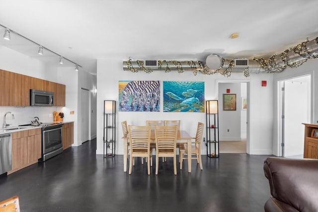dining space with track lighting, baseboards, and visible vents